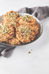 Vegan oatmeal cookies with dates and pumpkin seeds in silver plate, copy space. Healthy vegan food concept.