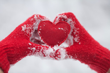 Woman making heart symbol with snowy hands. Red heart in woman hands. Valentines day. Love concept.