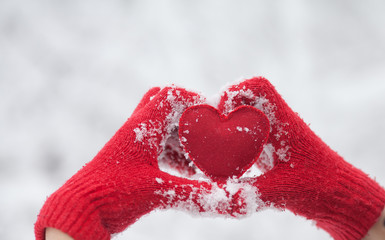 Woman making heart symbol with snowy hands. Red heart in woman hands. Valentines day. Love concept.