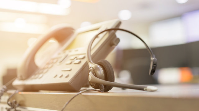 close up soft focus on headset with telephone devices at office desk for customer service support concept