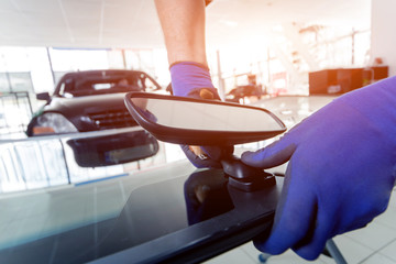 Automobile special workers replacing windscreen or windshield of a car in auto service station garage.