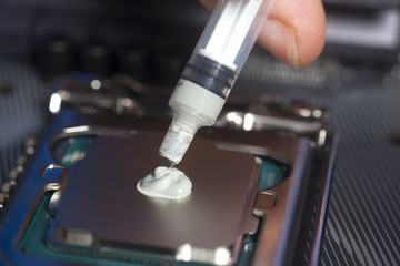 Fototapeta na wymiar Hand with syringe applying thermal paste on the CPU processor on motherboard