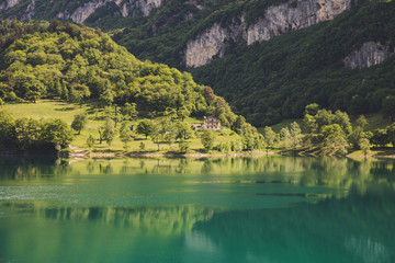 Fototapeta premium Lago di tenno with mountain and trees reflection in water. Tenno, Privincia di Trento, Trentino0Alto Adige, Italy