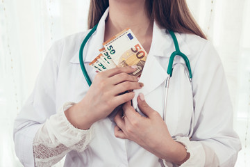 Doctor's hands hiding euro banknotes into jacket