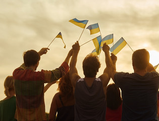 Back view, silhouette of ukrainian people with flags. Patriotic family against sunset background. - obrazy, fototapety, plakaty