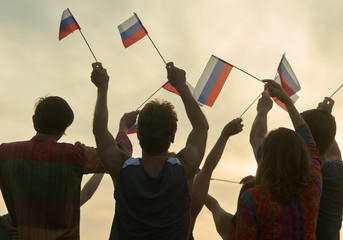 Crowd with russian flags. Evening sunny sky background.