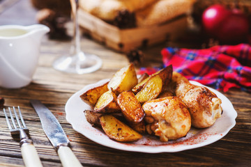 a tasty dish for the holiday, a new year or Christmas, baked potatoes with chicken legs, spices, paprika, sesame, bagel, olive oil, red wine on a wooden background