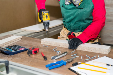 Woman carpenter making hole in wooden plank