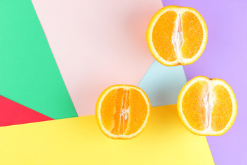 Fruits of oranges on a multicolored background, halves of oranges on colored paper. Copy space. Citrus in the style of pop art