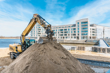 Big excavator and new building construction on blue sky background with free space. Building site with copy space