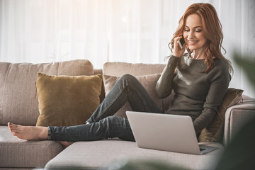 Full length portrait of carefree girl holding her mobile and communicating with smile and delight...