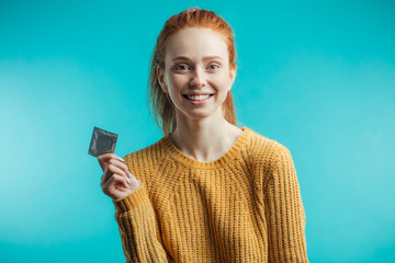 Attractive ginger adult woman holding condom calling to prevent sexually transmitted diseases or...