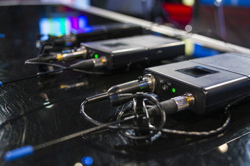 Three wireless microphone transmitter and three wireless microphone reciever on black table in tv studio - obrazy, fototapety, plakaty