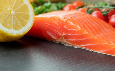 piece of salmon fillet with vegetables on slate background