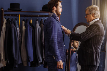 Handsome young groove male trying on classical mans suit getting ready to wedding ceremony