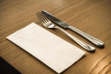 Fork, knife and paper napkin on a wooden table. Suitable for mockup.