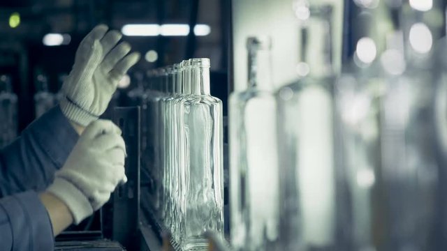 Glasshouse worker is measuring bottle necks and removes defective bottles