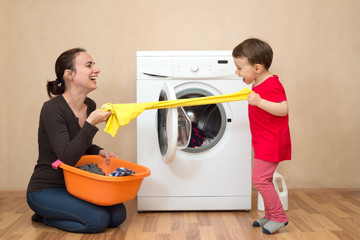 Mother and daugher playing near the washing machine
