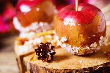 winter and New Year delicacy, dessert, red apple in caramel with sea salt, honey and spices on a wooden background