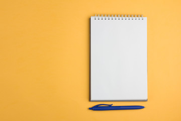Blank notebook with pen on yellow pastel background. Flat lay concept. Copy space