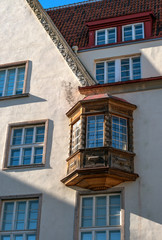 Fototapeta na wymiar Bay window on the facade of a medieval house in Tallinn. Estonia. The Bay window is made of wood, the house is stone. The roof of the house is lined with clay tiles