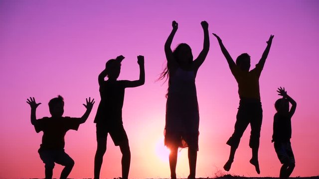 silhouette of five kids family jumping at sunrise