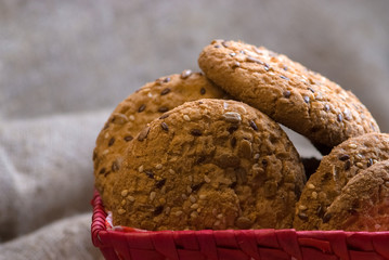 homemade oat cookies with sunflower seeds in and near checkered basket on burlap background