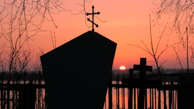A monument in the cemetery on the sunset background