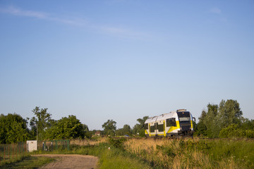 Szynobus skąpany w promieniach słońca jedzie wzdłuż drogi  © Erap2