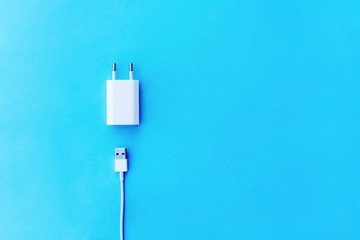  white сable phone chargers on blue background.  Top view. Objects on a simple background