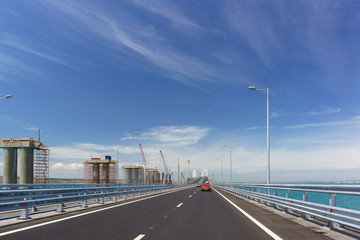 Cars approaching the rise of the arch of the new automobile bridge connecting the banks of the Kerch Strait between Taman and Kerch