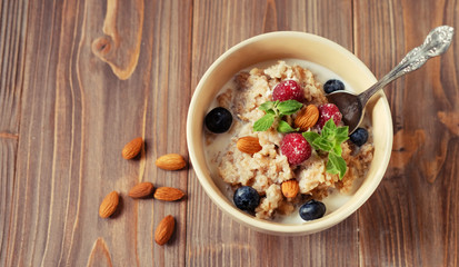 healthy eating and diet concept: Oatmeal porridge in bowl topped with fresh blueberries and raspberries on wooden table.