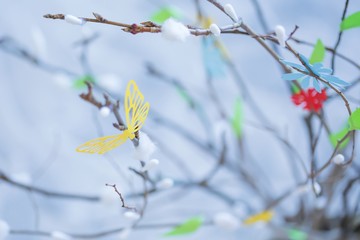 Paper butterfly, flowers and leaves on a blooming tree.
