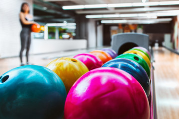 Naklejka na ściany i meble Rack Of Colorful Balls At A Bowling Alley with blurred player in background