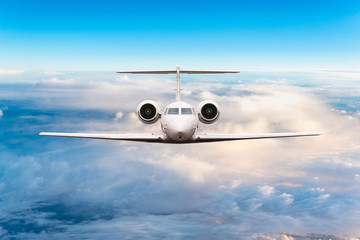 Front view of aircraft. Privat jet in flight. The passenger plane flies high above the clouds and blue sky. Luxury travel concept