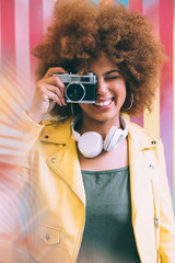 Mixed race woman in a colorful artwork background wall holding a vintage camera