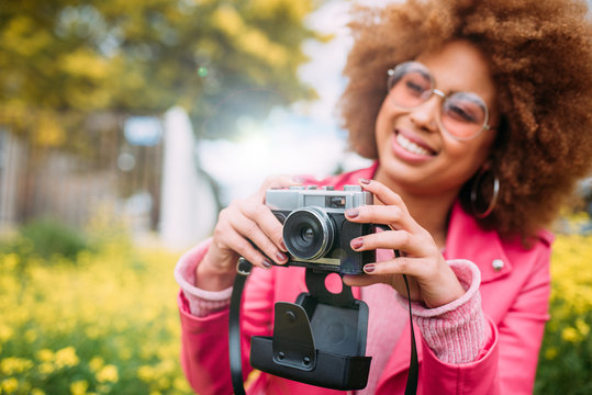 Happy mixed race woman in a beautiful flower field holding a vintage camera
