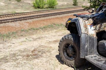 Close-up ATV or quad bike wheel standing on hill. Beautiful cross-country landscape with railway on background. Extreme travel and adventure concept