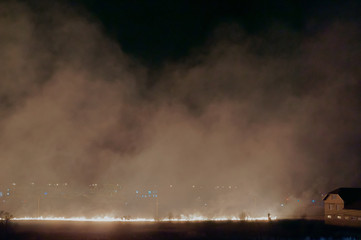 Fire in the field at night. Burning grass on the field. The smoke from the burning field.