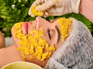 Facial mask from fresh fruits for woman. Girl in medical hat give slices of avocado, grapefruit and kiwi as ingradients for face. Close-up. Acceleration of hair and eyebrows growth.