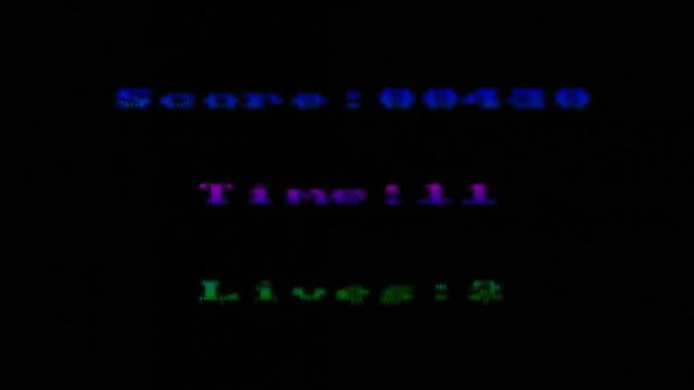 Analog capture (intentional heavy distortion fx): a video arcade game screen detail, showing an increasing score, a decreasing time, and the remaining lives of the player.
