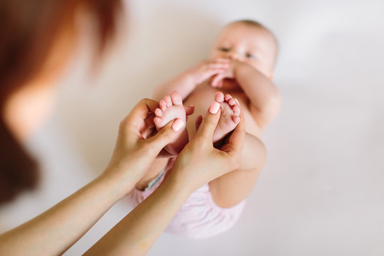 Mother hand massaging foot of her baby on white background