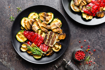 Grilled vegetable salad. Salad of barbecued zucchini, eggplant, sweet pepper, onion and mushrooms on black plate