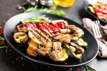 Grilled vegetable salad. Salad of barbecued zucchini, eggplant, sweet pepper, onion and mushrooms on black plate