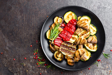 Grilled vegetable salad. Salad of barbecued zucchini, eggplant, sweet pepper, onion and mushrooms on black plate