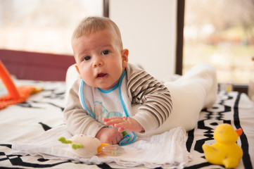 3 months old baby boy plays with his toys and looks at the camera