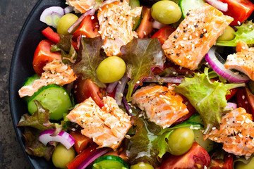 Salad with fish. Fresh vegetable salad with salmon fish fillet. Fish salad with salmon fillet and fresh vegetables on plate