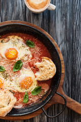 top view of delicious fried eggs in pan and cup of coffee on wooden table