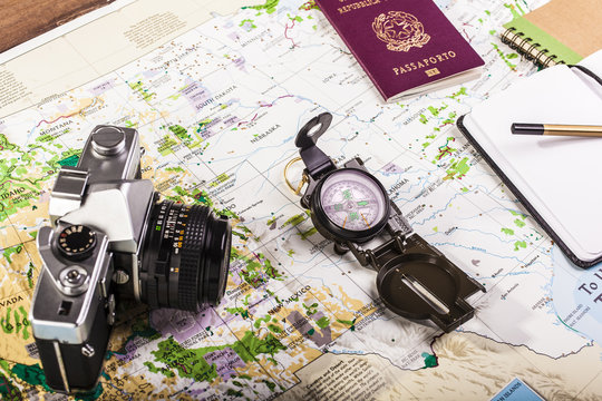 Compass, passport, photo camera and block notes on map