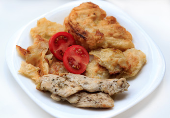 Chicken fillet, cabbage fried in egg and tomatoes, vib on the side on a white plate